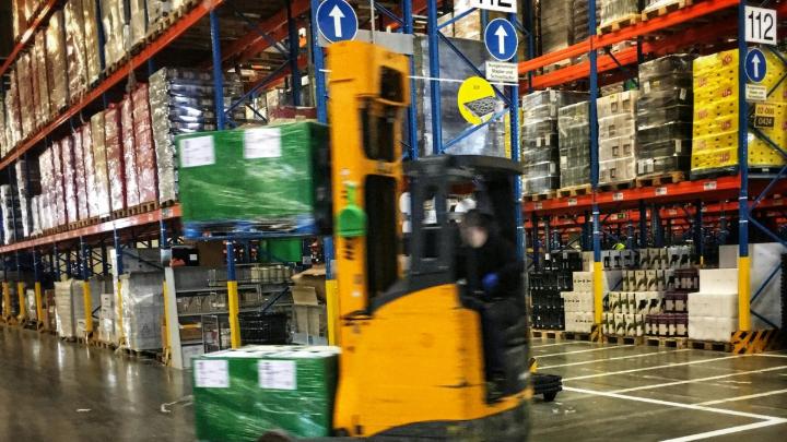 Targonca raklappal a színes raktári polcsorok között